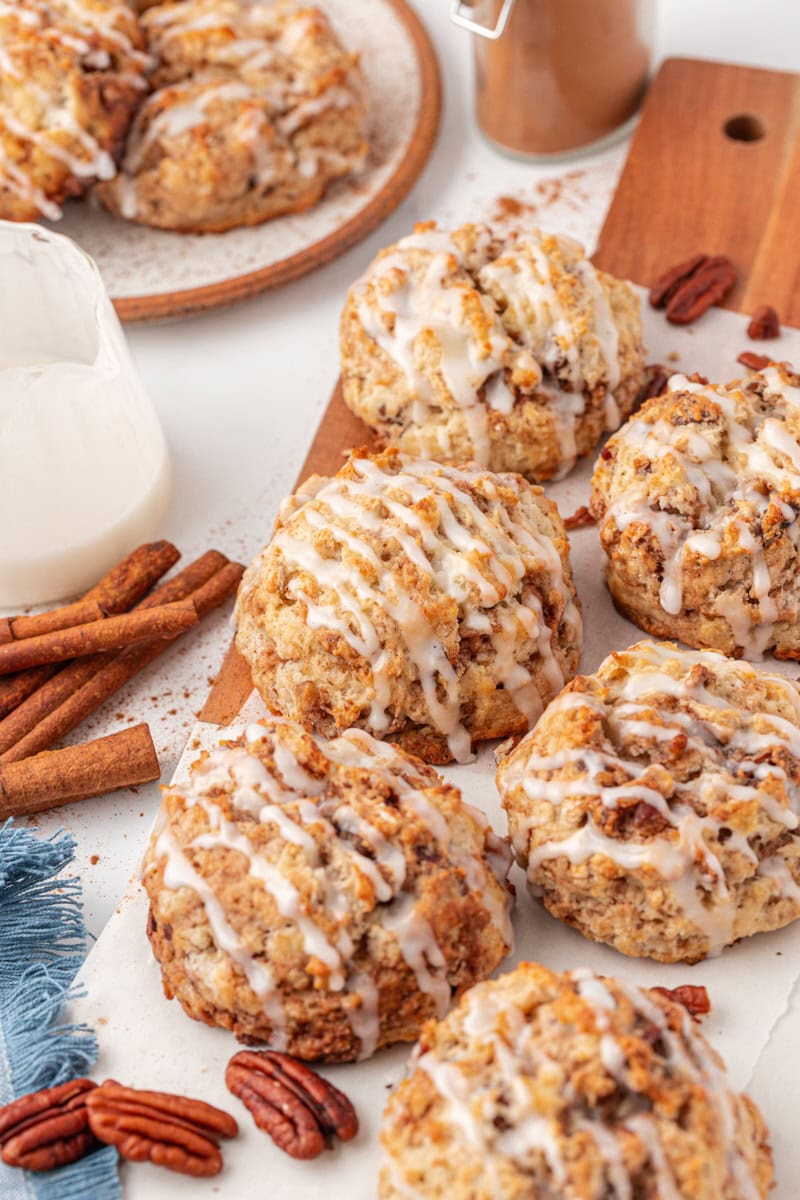 cinnamon bun scones on a wooden board with more scones on a plate in the background