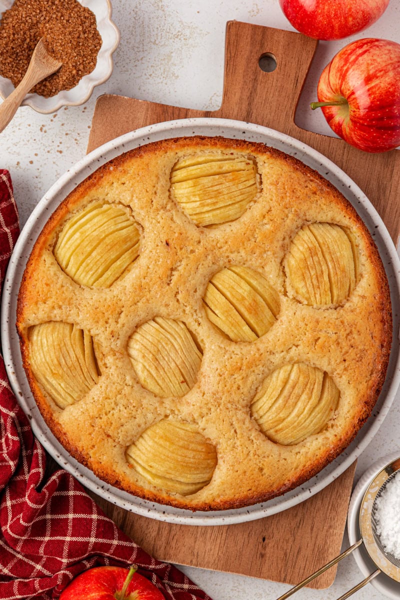 overhead view of freshly baked German apple cake in a springform pan set on a wooden board