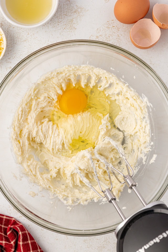 overhead view of egg added to creamed butter and sugar in a glass mixing bowl