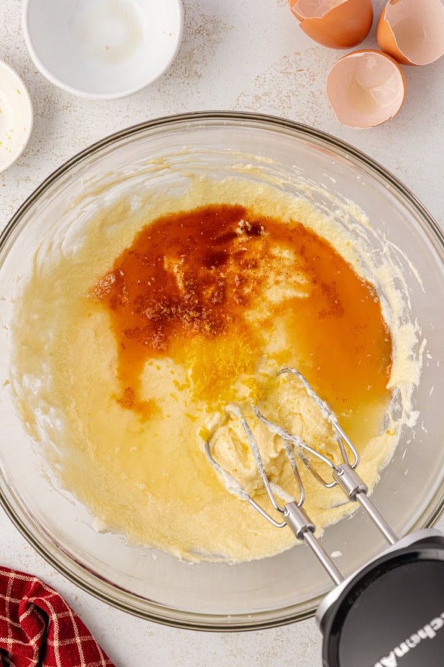 overhead view of vanilla, almond extract, lemon zest, and lemon juice added to partially mixed cake batter