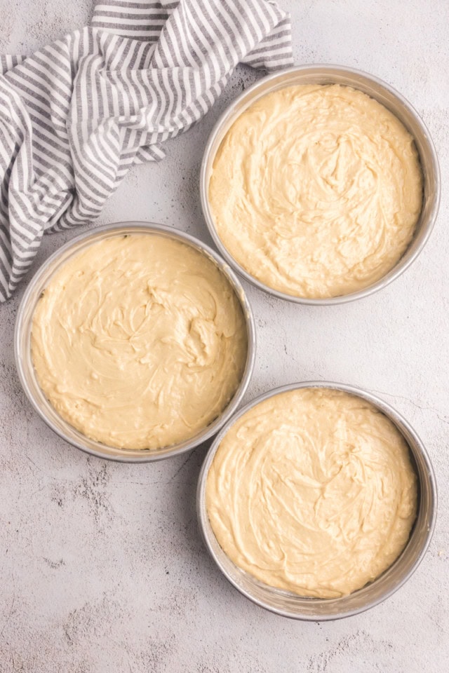 overhead view of Italian cream cake batter divided into three round cake pans ready to go into the oven