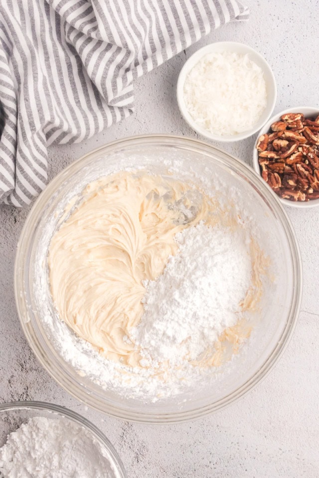 overhead view of confectioners' sugar added to creamed butter and cream cheese