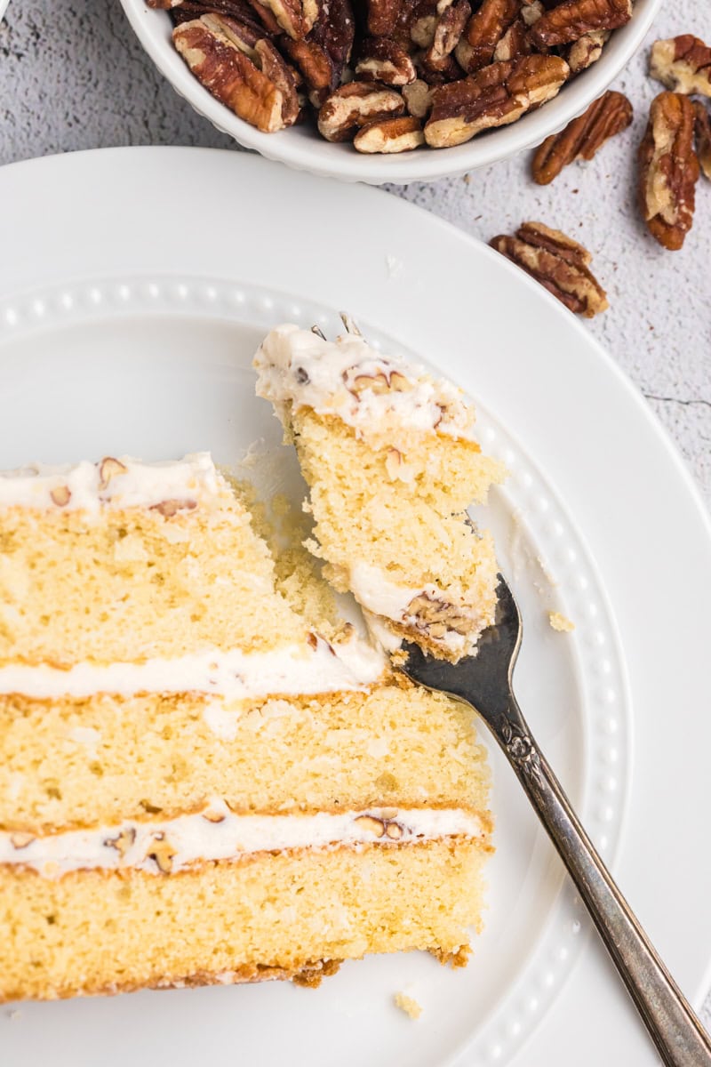overhead view of a slice of Italian cream cake on a plate with a bite on a fork