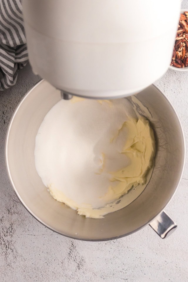 overhead view of sugar added to creamed butter in the bowl of a stand mixer