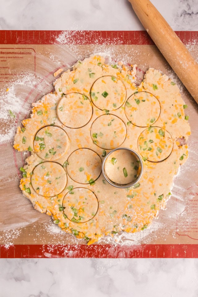 overhead view of jalapeño cheddar biscuit dough being cut into rounds on a lightly floured surface
