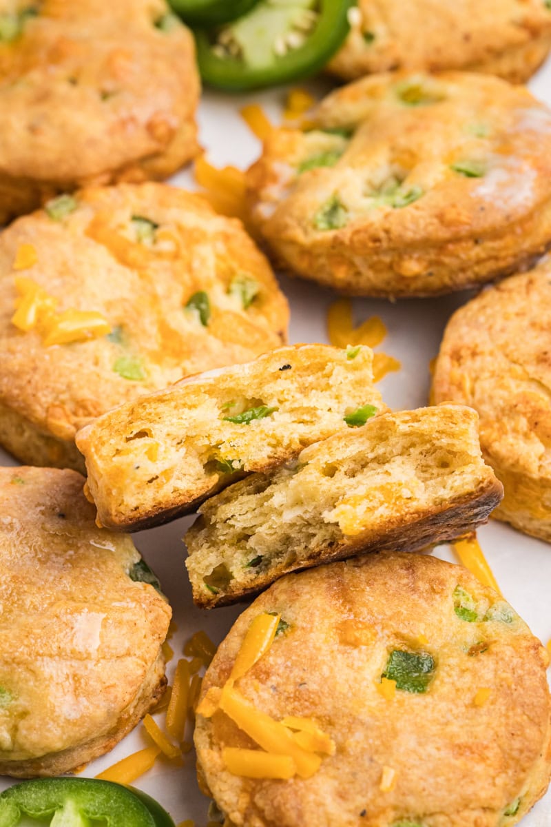 a jalapeño cheddar biscuit cut in half to show the layers, cheese, and peppers, with more biscuits surrounding