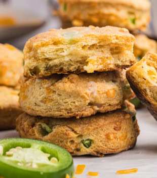 stack of three jalapeño cheddar biscuits with a bite missing from the top biscuit