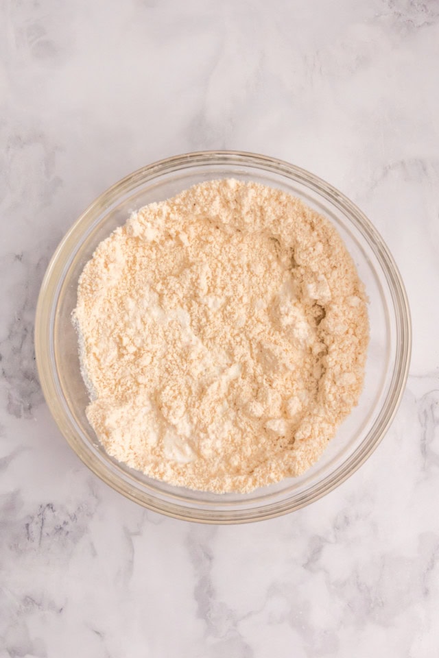 overhead view of buttermilk added to biscuit dough in a glass mixing bowl