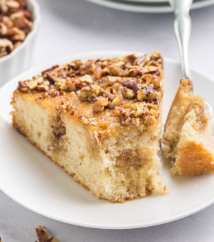 a slice of pecan pie coffee cake on a white plate with a bite on a fork