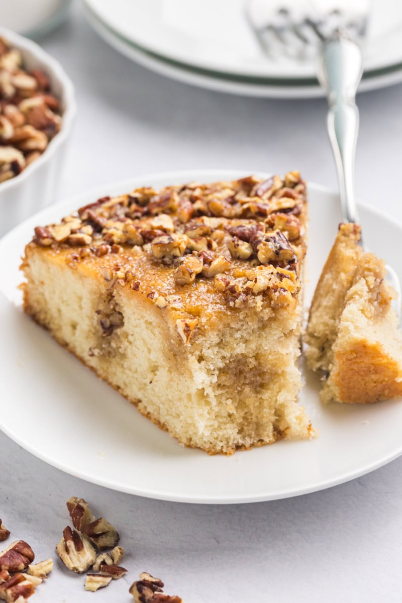 a slice of pecan pie coffee cake on a white plate with a bite on a fork