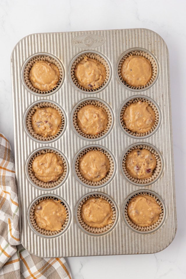 overhead view of pecan praline muffin batter divided into a 12-cup muffin pan