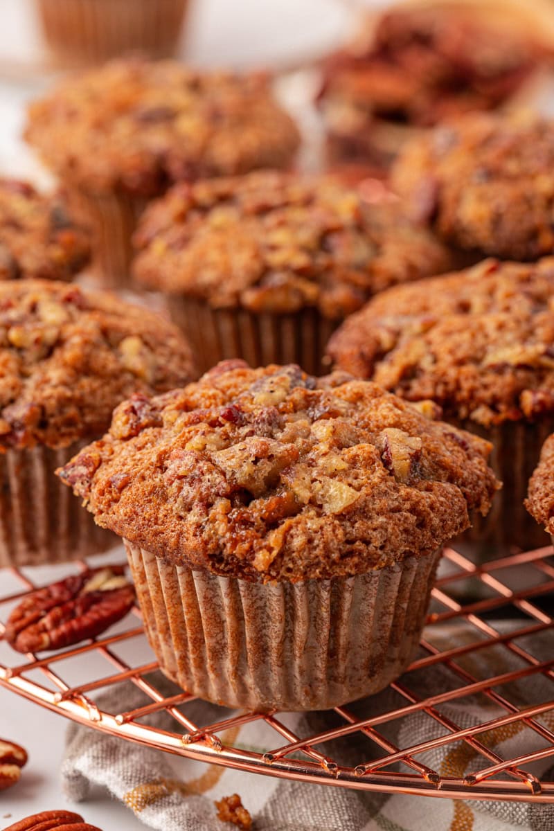 close-up of a pecan praline muffin on a wire rack with more muffins in the background