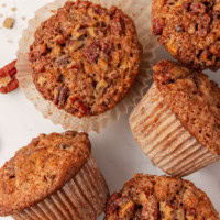 overhead view of five pecan praline muffins on a white surface