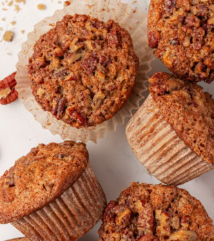 overhead view of five pecan praline muffins on a white surface