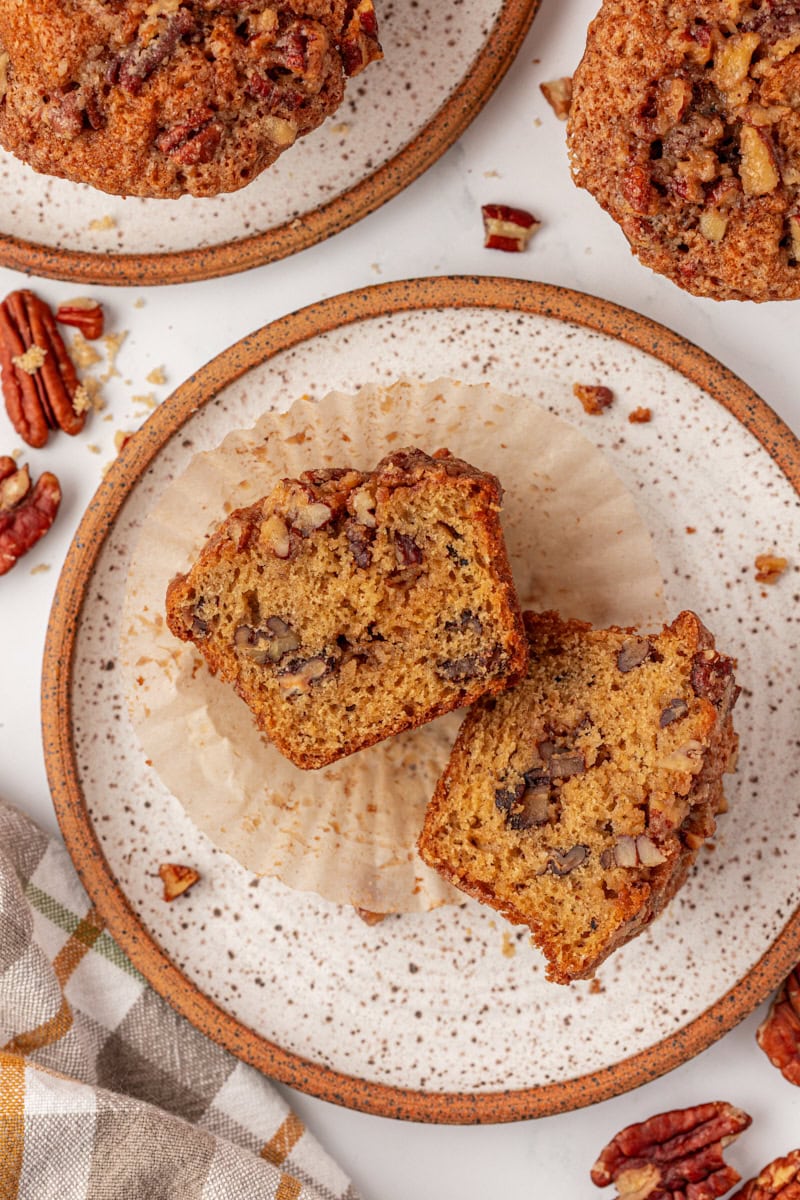 overhead view of a pecan praline muffin cut in half on a brown-rimmed white plate