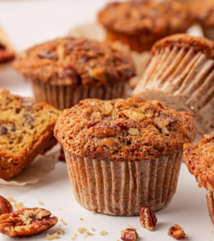 a pecan praline muffin on a white surface with more muffins in the background