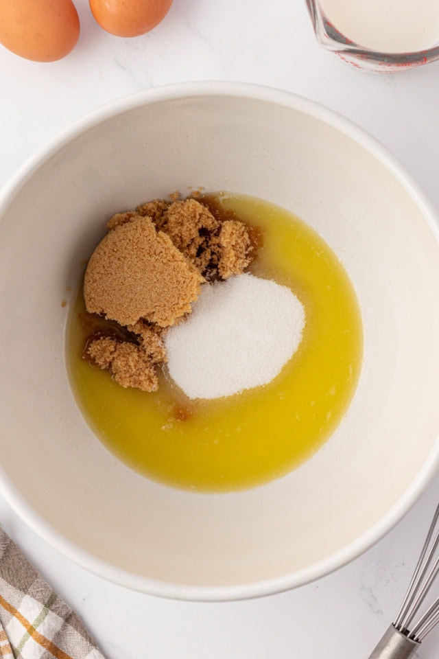 overhead view of melted butter, brown sugar, and sugar in a white mixing bowl
