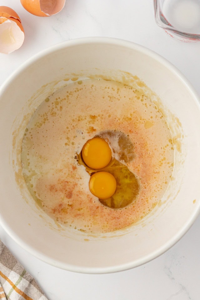 overhead view of eggs, milk, and vanilla added to partially mixed muffin batter