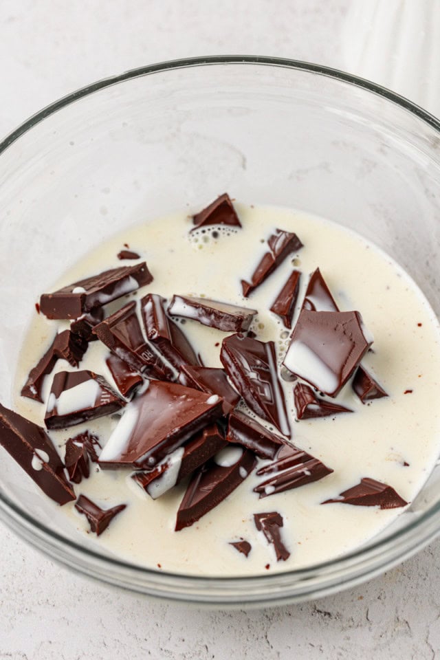 warmed cream poured over chopped chocolate in a glass bowl