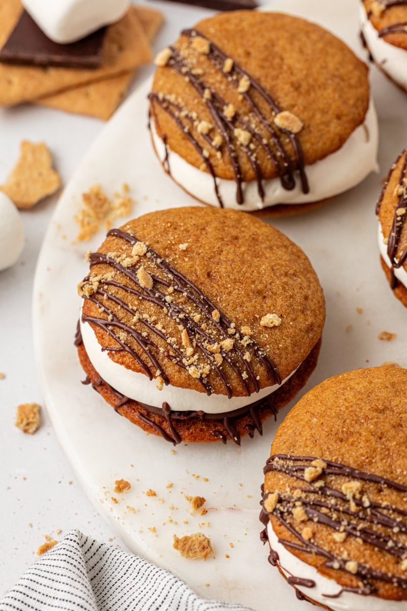 three s'mores whoopie pies on a white cake stand