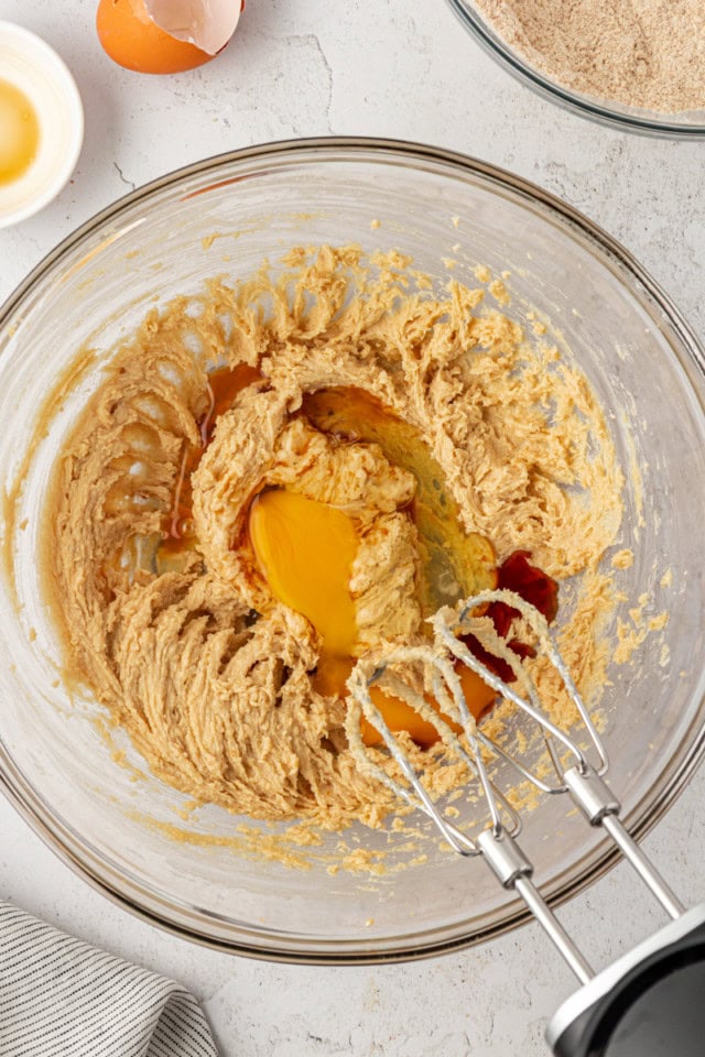 overhead view of egg and vanilla added to creamed butter and sugar in a glass mixing bowl