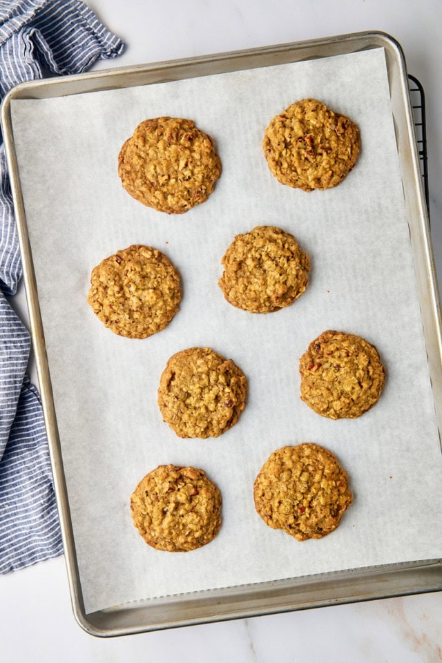 overhead view of freshly baked brown butter maple oatmeal cookies on a parchment-lined baking sheet