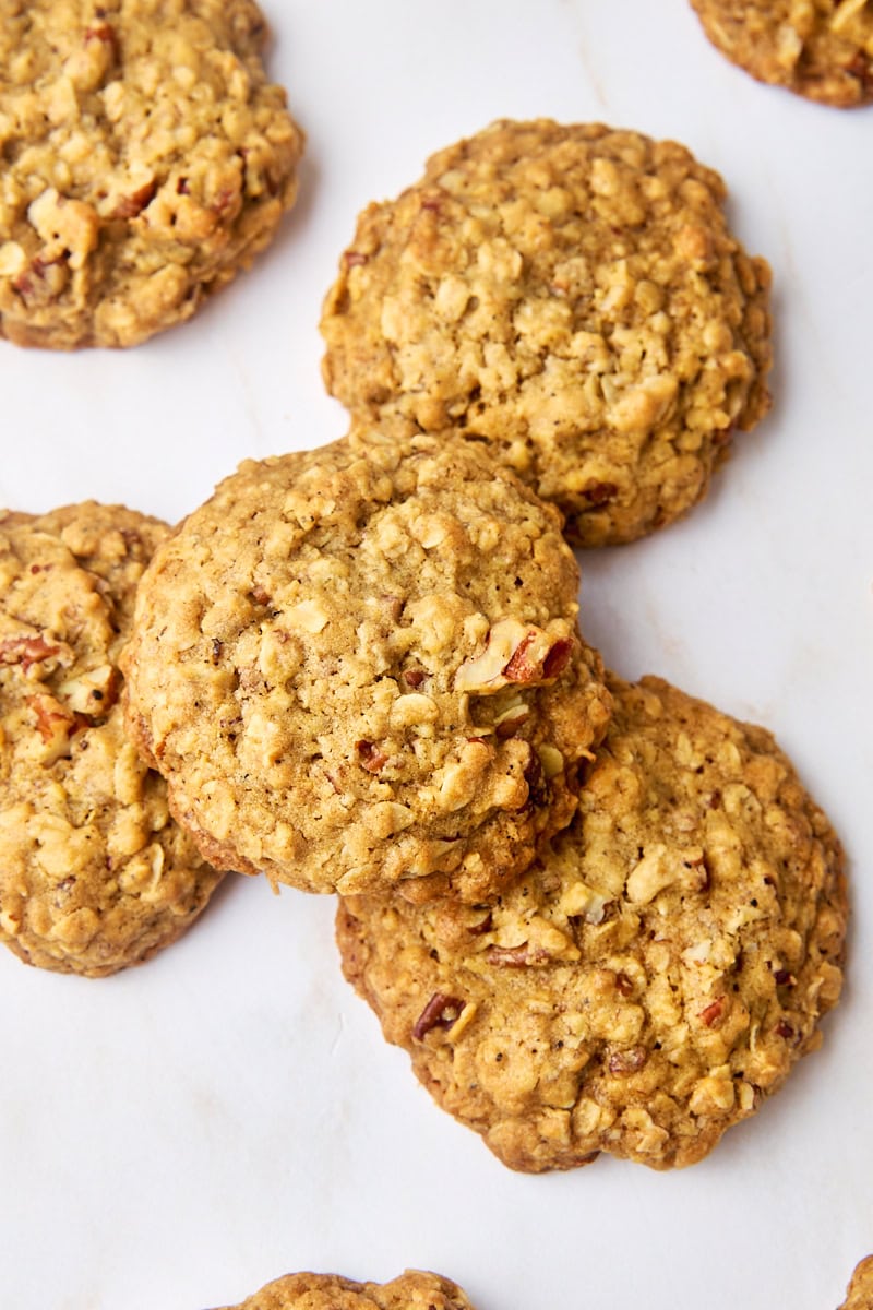 overhead view of several brown butter maple oatmeal cookies scattered on a white surface