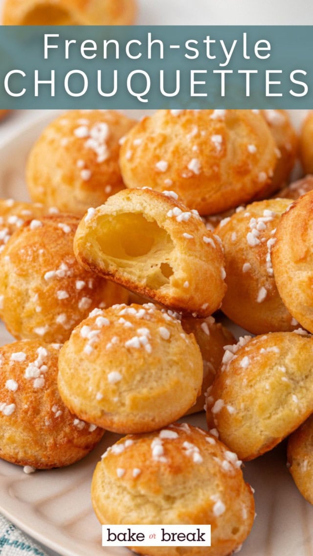 A close-up of golden brown chouquettes topped with pearl sugar, arranged on a plate. One puff is torn open to show the airy, hollow center. Text overlay reads “French-style Chouquettes.”