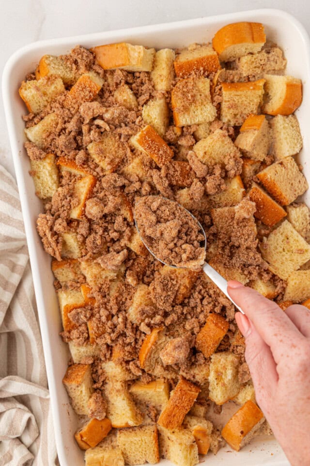 overhead view of crumb topping being sprinkled over baked French toast before baking