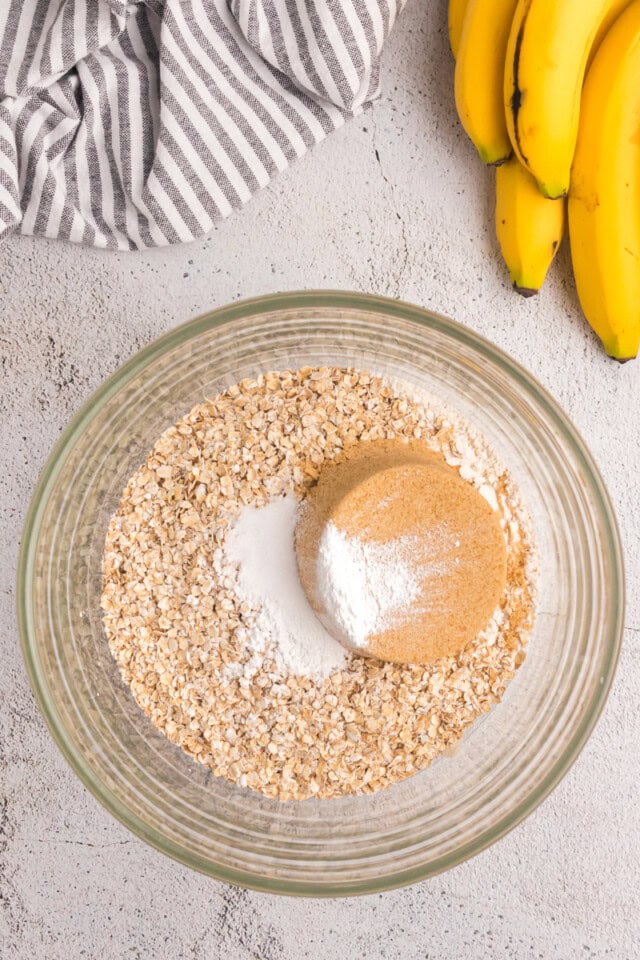 overhead view of flour, oats, brown sugar, baking powder, and salt in a glass mixing bowl
