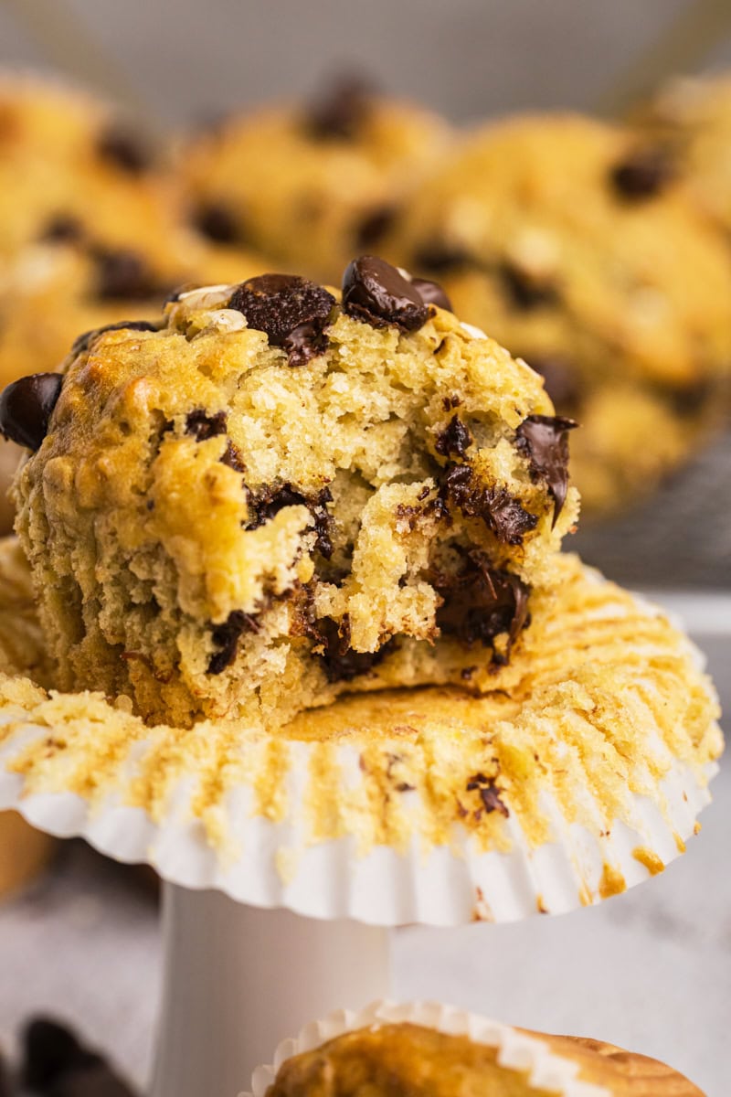 a banana oatmeal chocolate chip muffin with a bite missing; more muffins partially visible in the background