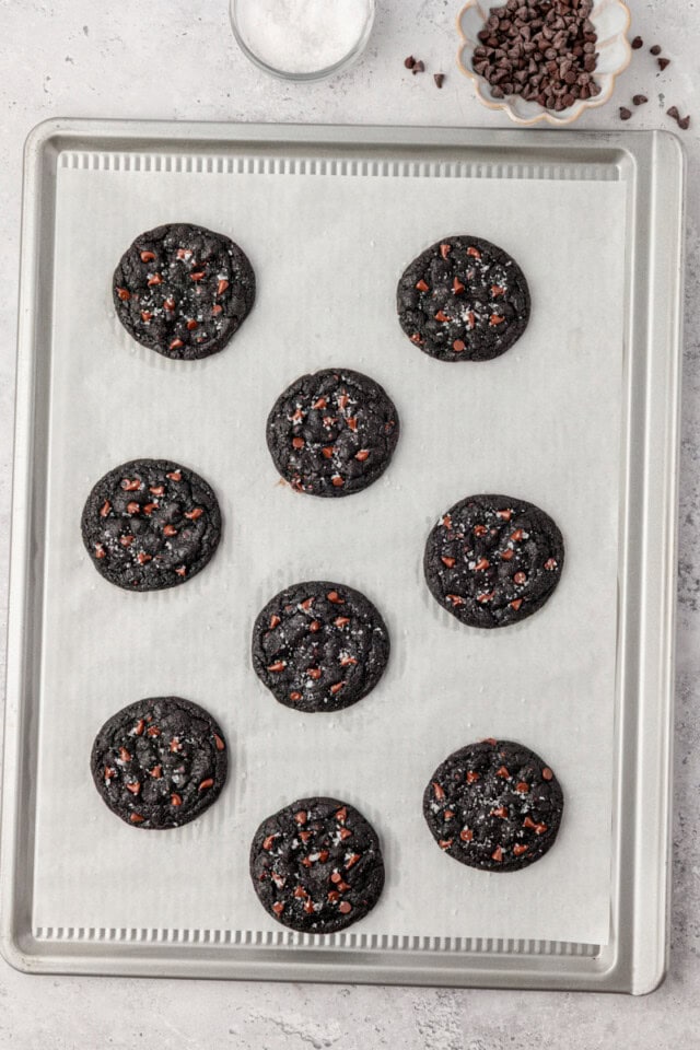 overhead view of freshly baked black cocoa cookies on a parchment-lined baking sheet