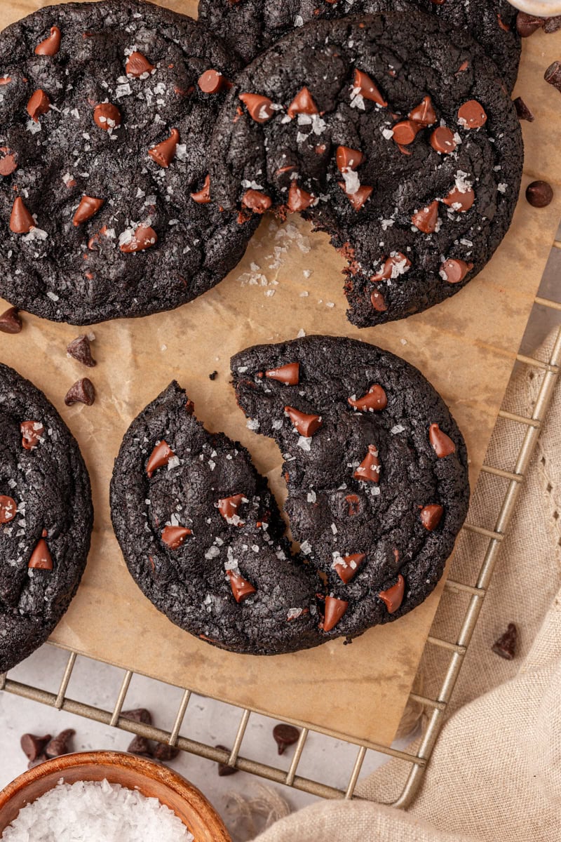 a black cocoa cookie cut in half on parchment paper with more cookies surrounding