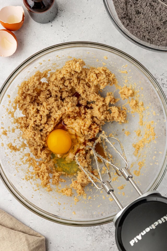 overhead view of egg added to creamed butter and sugar in a glass mixing bowl