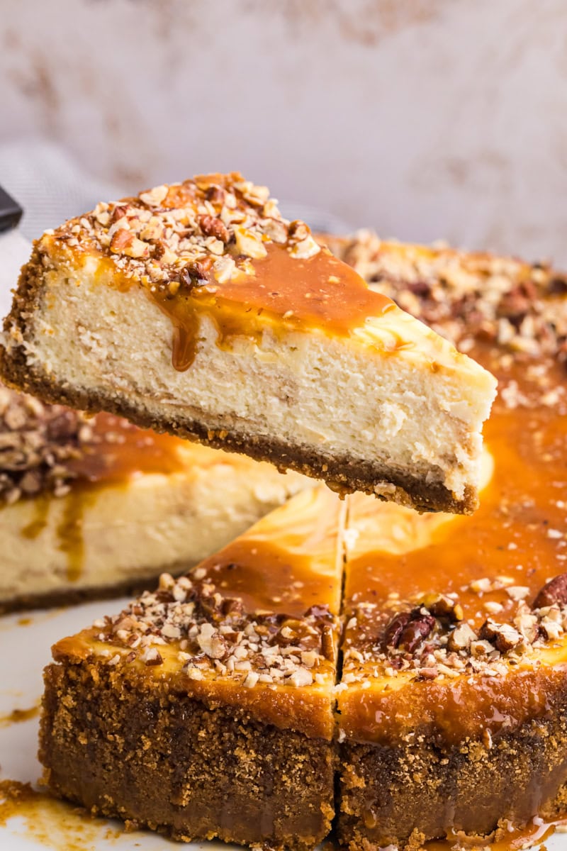 a slice of bourbon caramel swirl cheesecake being lifted away from the remaining cheesecake
