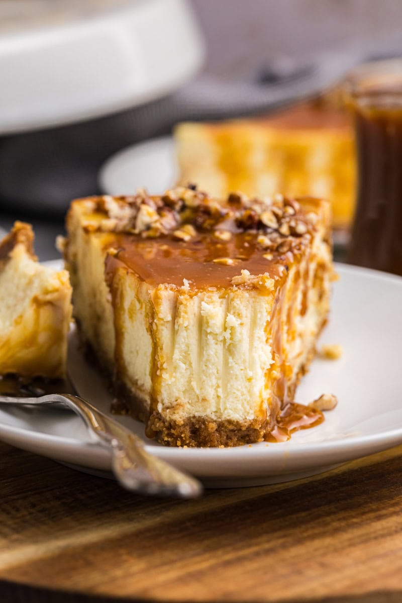 a slice of bourbon caramel swirl cheesecake on a white plate with a bite on a fork