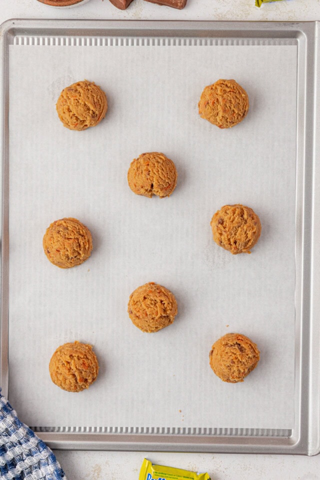 overhead view of Butterfinger cookie dough scooped onto a parchment-lined baking sheet, ready to go into the oven