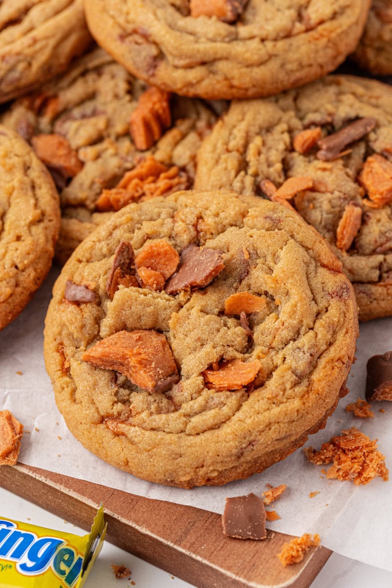 Butterfinger cookies piled on a parchment-lined wooden serving board