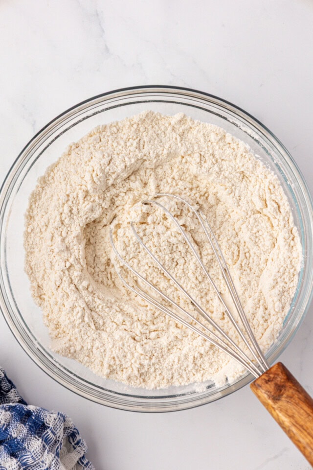 overhead view of flour, baking soda, and salt whisked together in a glass mixing bowl