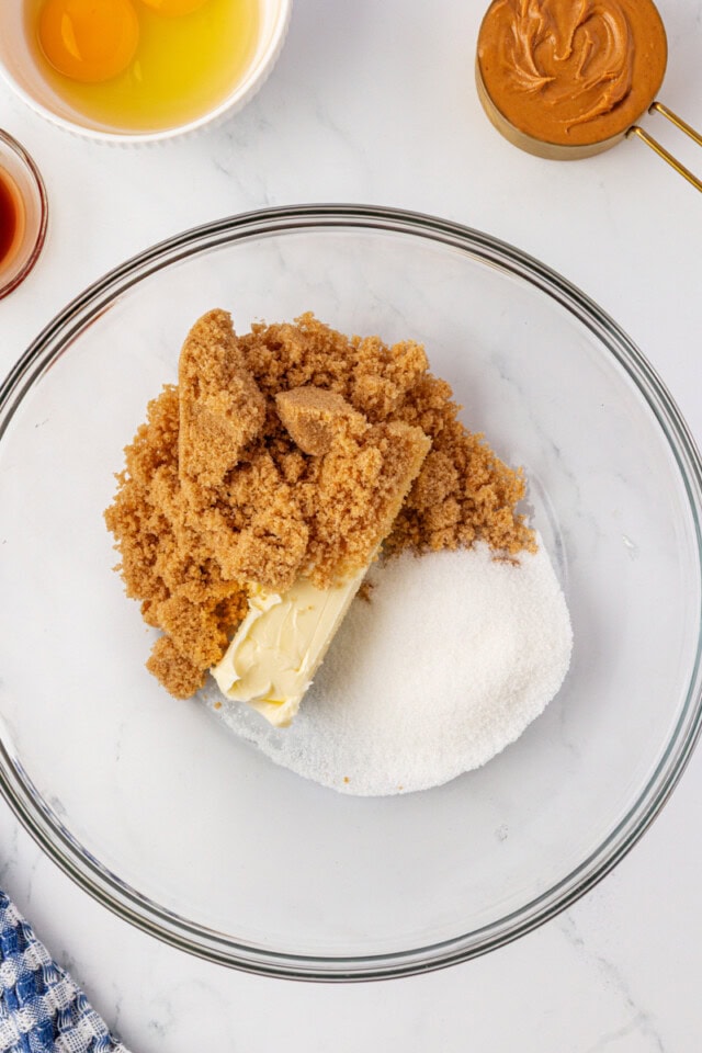 overhead view of butter, sugar, and brown sugar in a glass mixing bowl