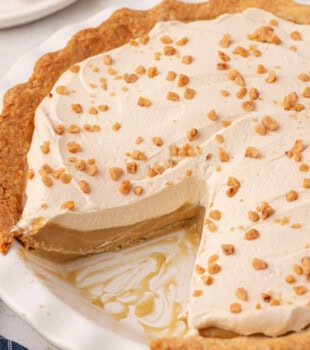 butterscotch pie with a slice missing in a white pie plate