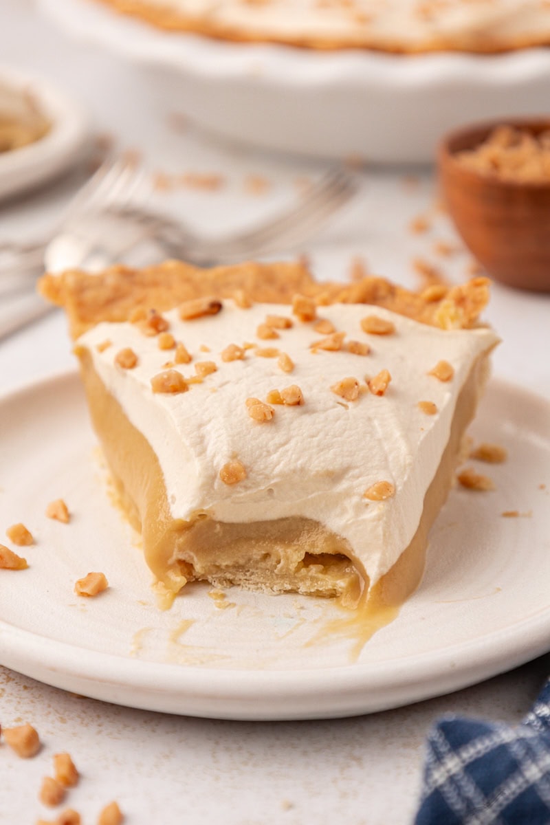 a slice of butterscotch pie with a bite missing on a white plate