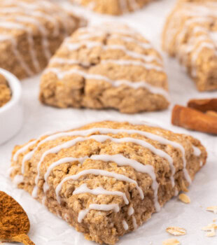 a cinnamon oat scone on parchment paper with more scones in the background