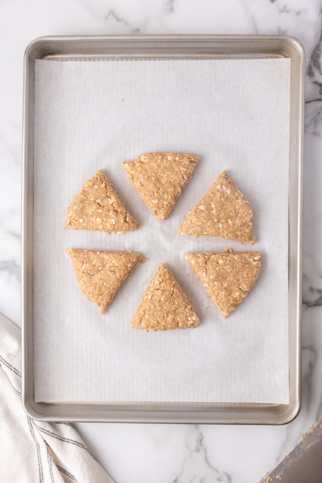 overhead view of cinnamon oat scones on a parchment-lined baking sheet ready to go into the oven