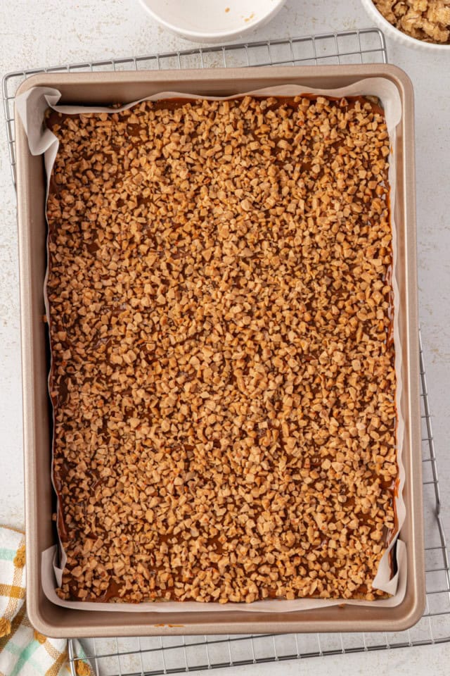 overhead view of toffee bits sprinkled over dulce de leche and an oat crust
