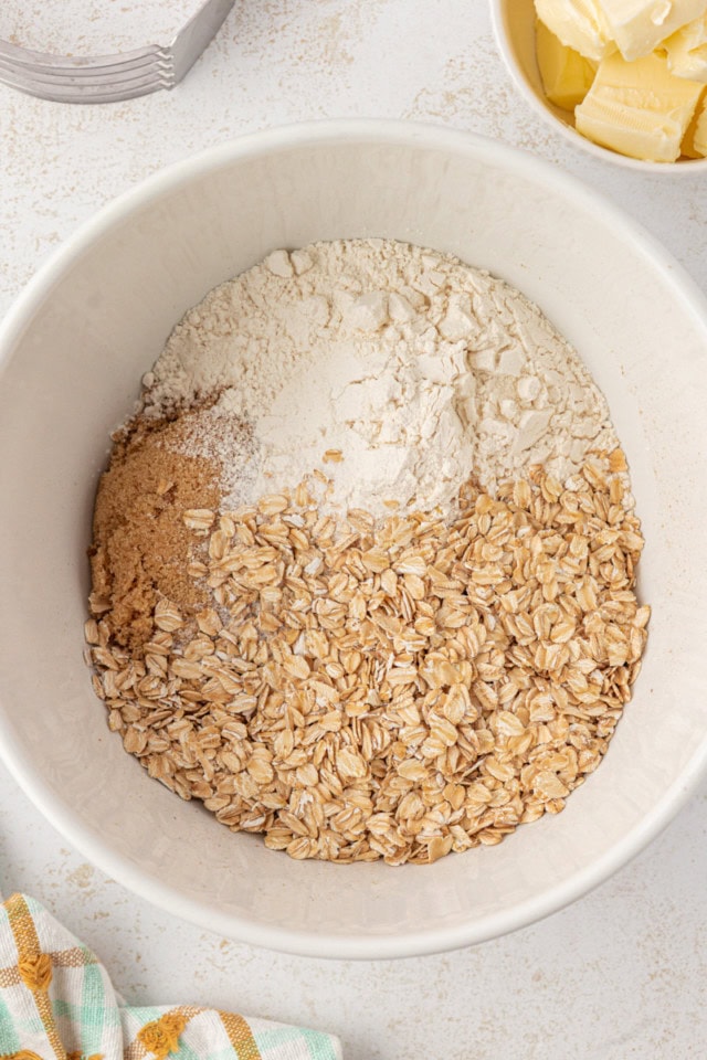 overhead view of flour, brown sugar, oats, and salt in a white mixing bowl