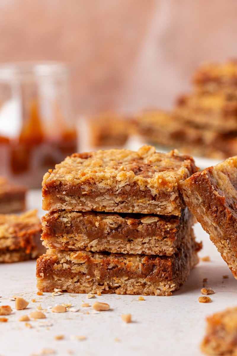 stack of three dulce de leche bars on a white surface with more bars in the background