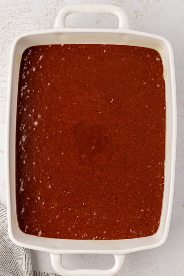 overhead view of chocolate cake batter in a white baking pan, ready to go into the oven