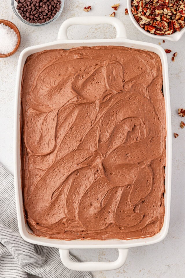 overhead view of chocolate frosting spread over chocolate cake in a white rectangular pan
