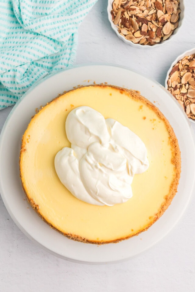 overhead view of sour cream glaze on top of amaretto cheesecake, ready to be spread to cover the top